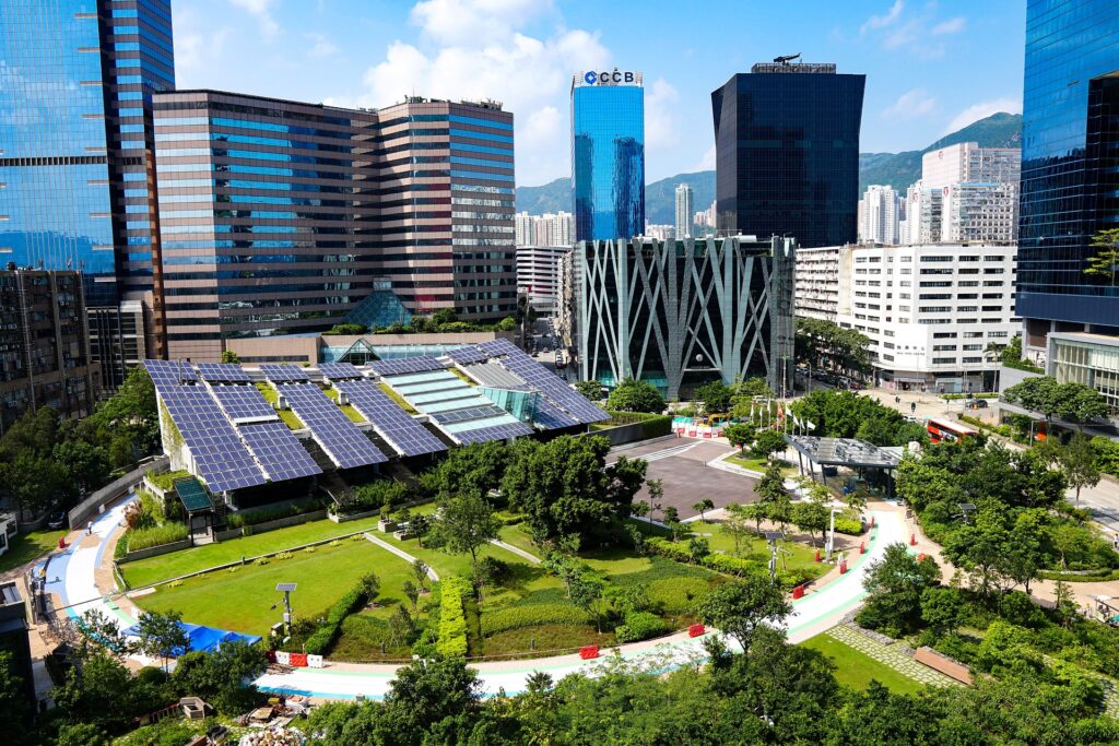 Grüner Park an einem sonnigen Tag mit Fokus auf ein Gebäude mit Photovoltaik Anlagen